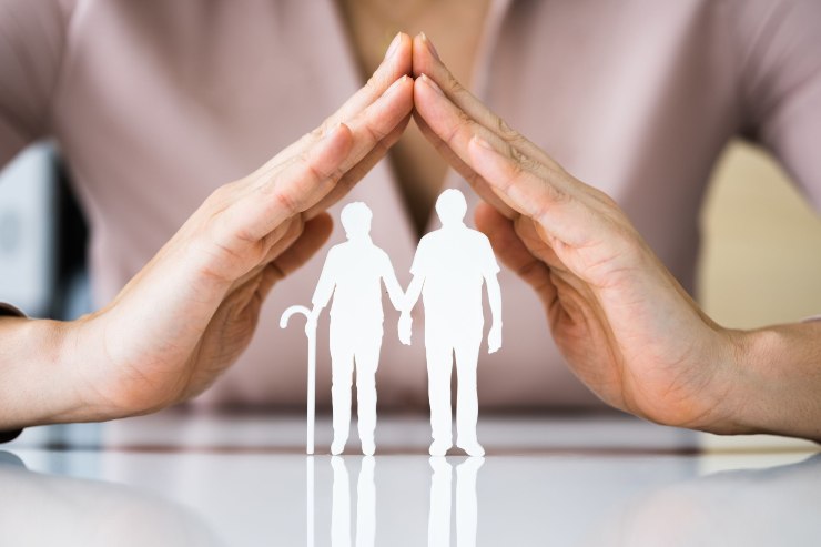 Due sagome di anziani, protetti da due mani