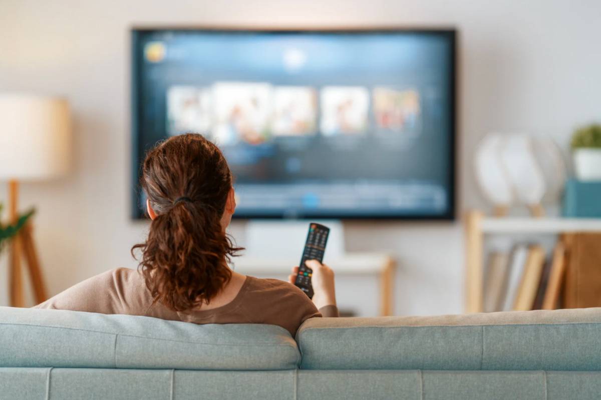 Donna che punta telecomando verso il televisore