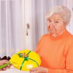 donna anziana con espressione delusa mentre le consegnano una padella in regalo